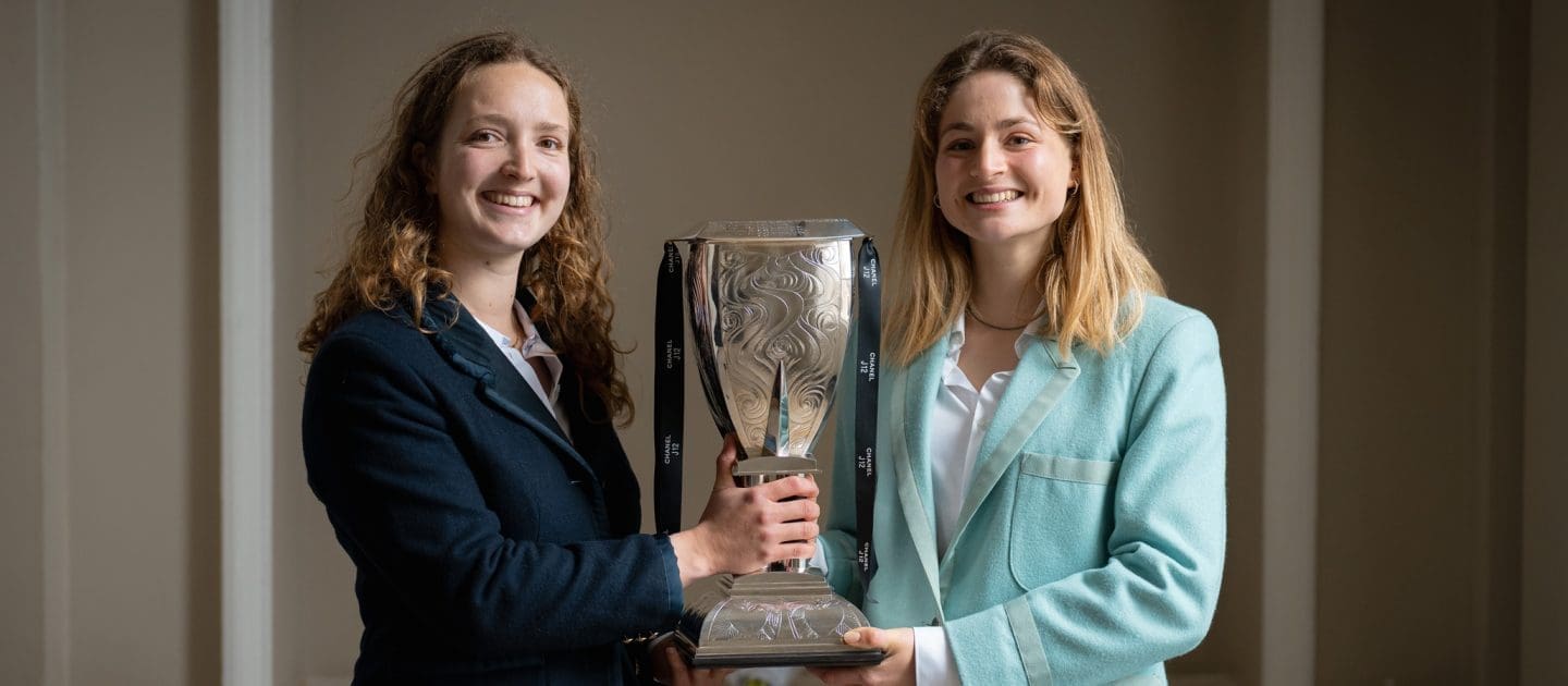 Female Oxford and Cambridge athletes holding the Women's Boat Race trophy